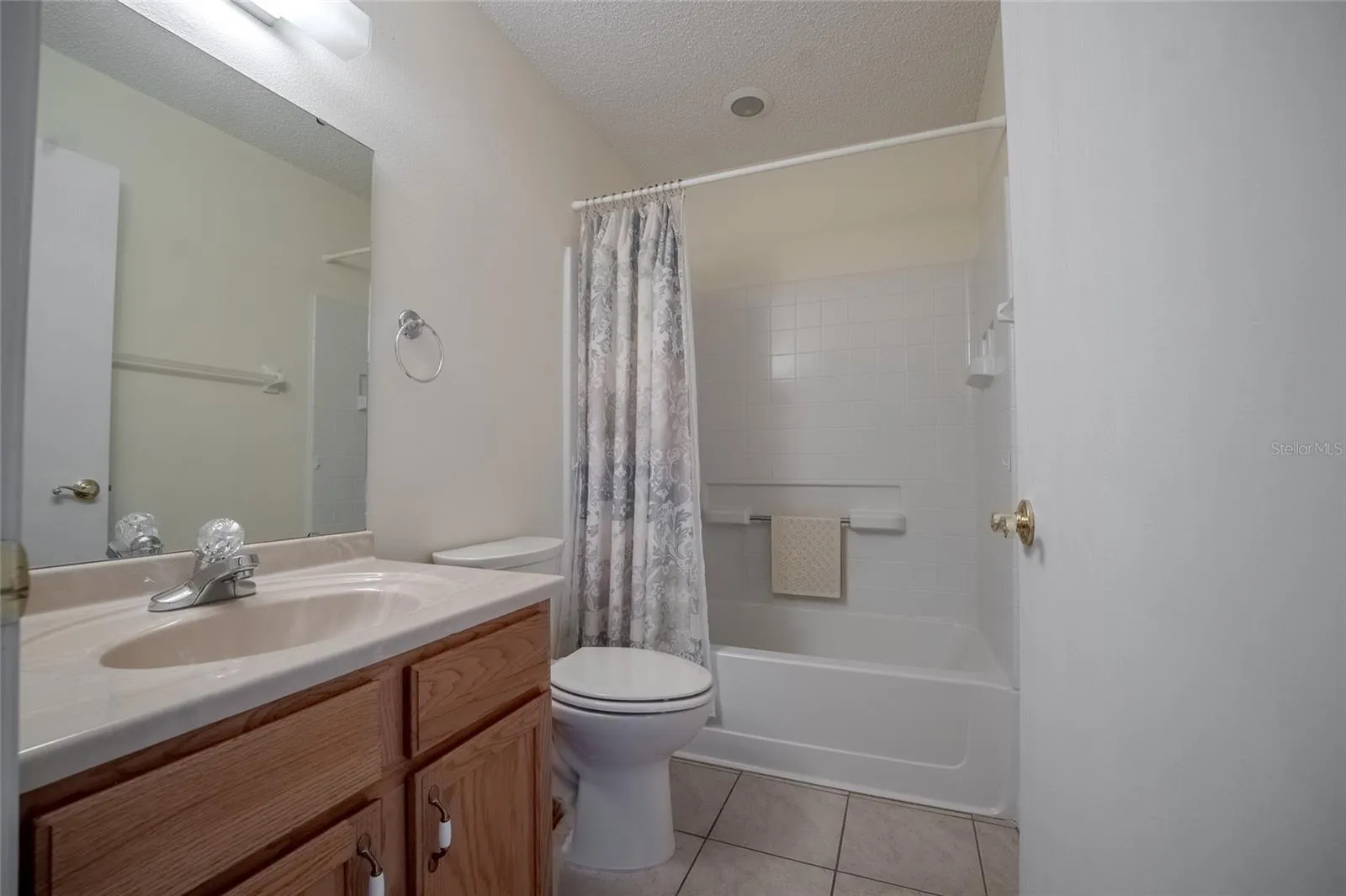 Guest bathroom with solid countertop, tile floor and tub/shower combo.