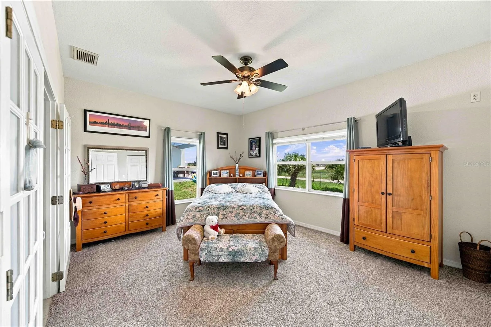 Beautifully appointed bedroom featuring panoramic views, an ensuite bathroom, a ceiling fan, and window treatments.