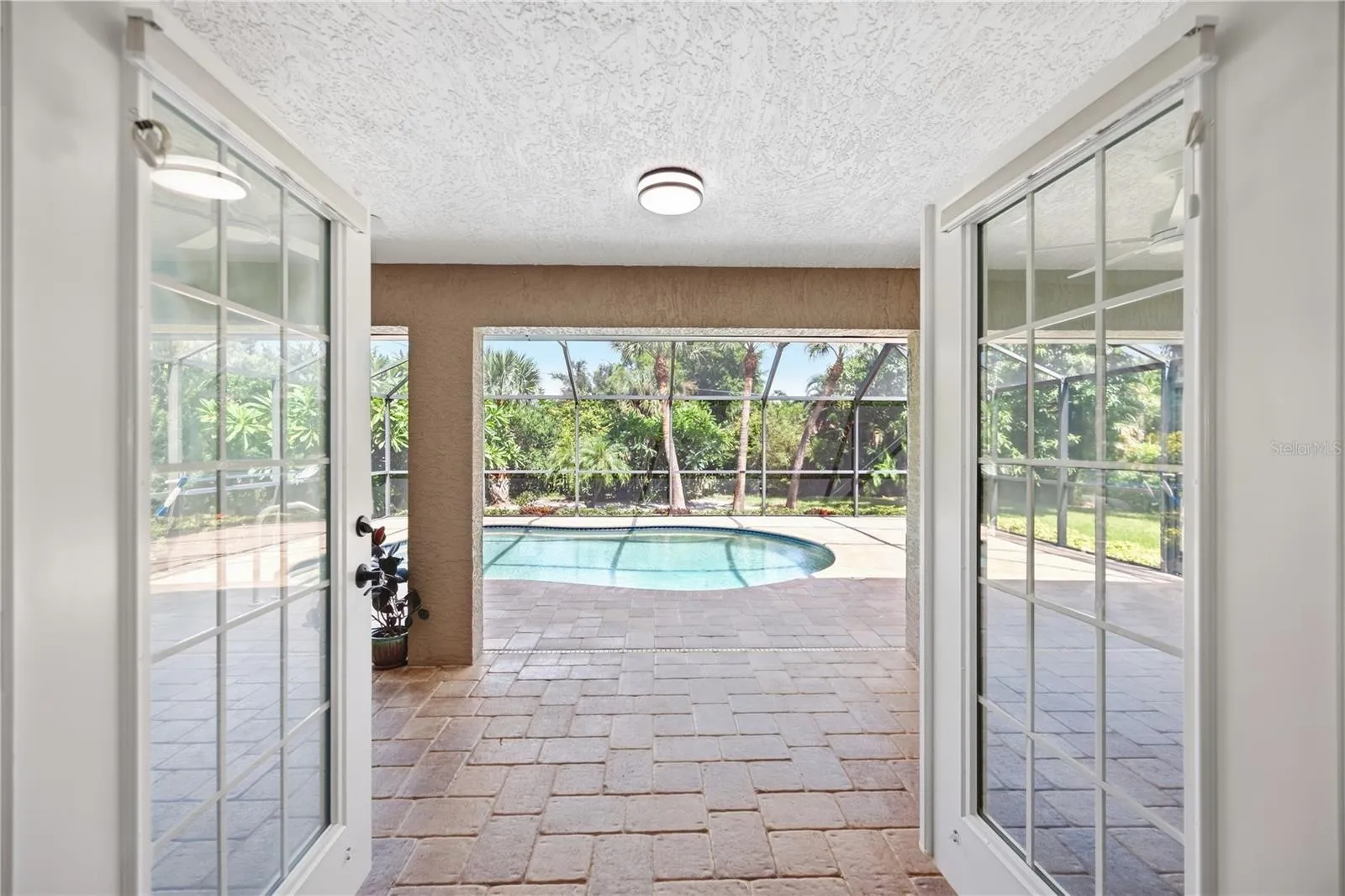 French doors open from bonus room/study, leading to the lanai and pool