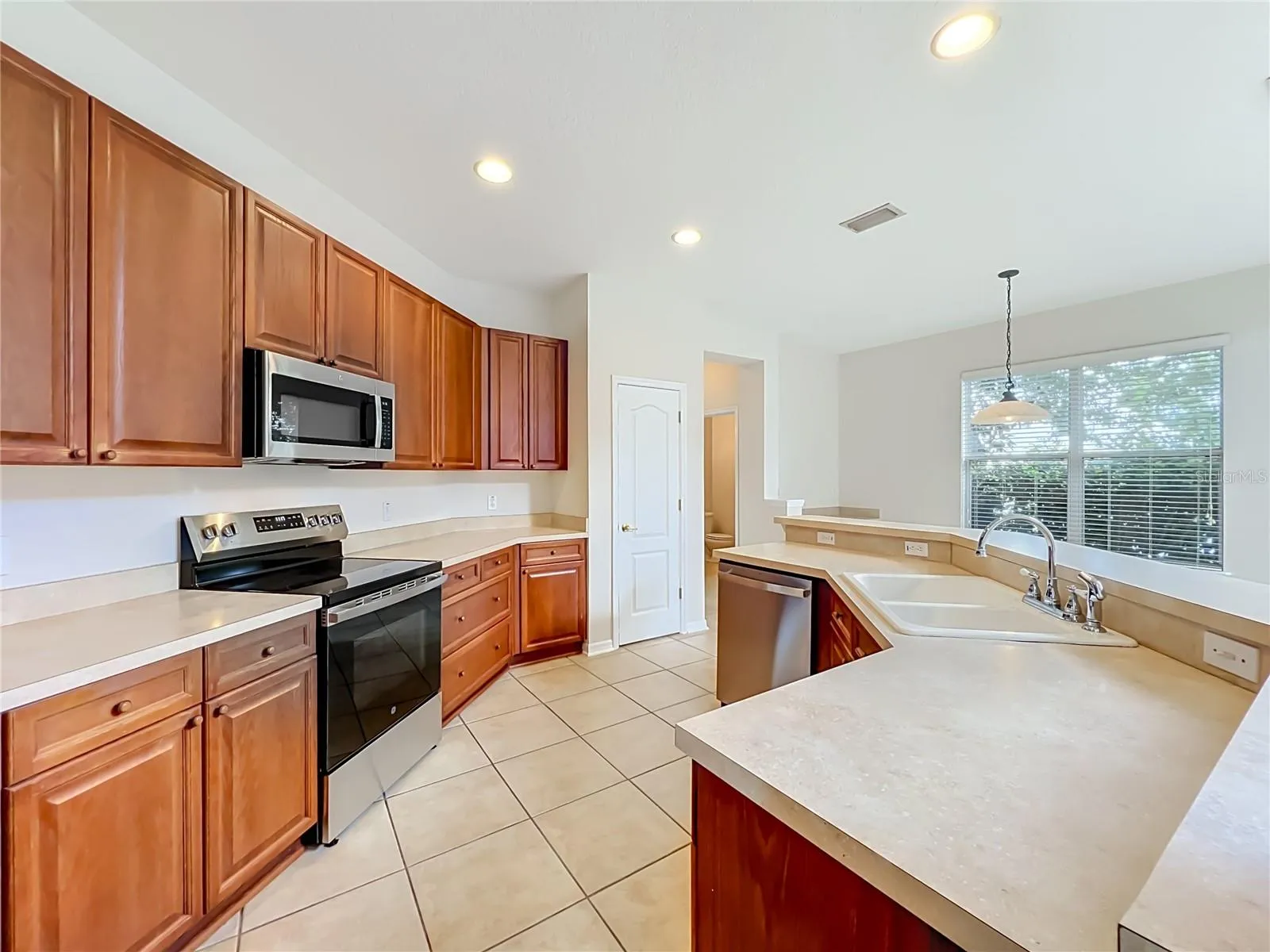 Wood cabinets, new appliances, closet pantry, a long breakfast bar, and ceramic tile floors