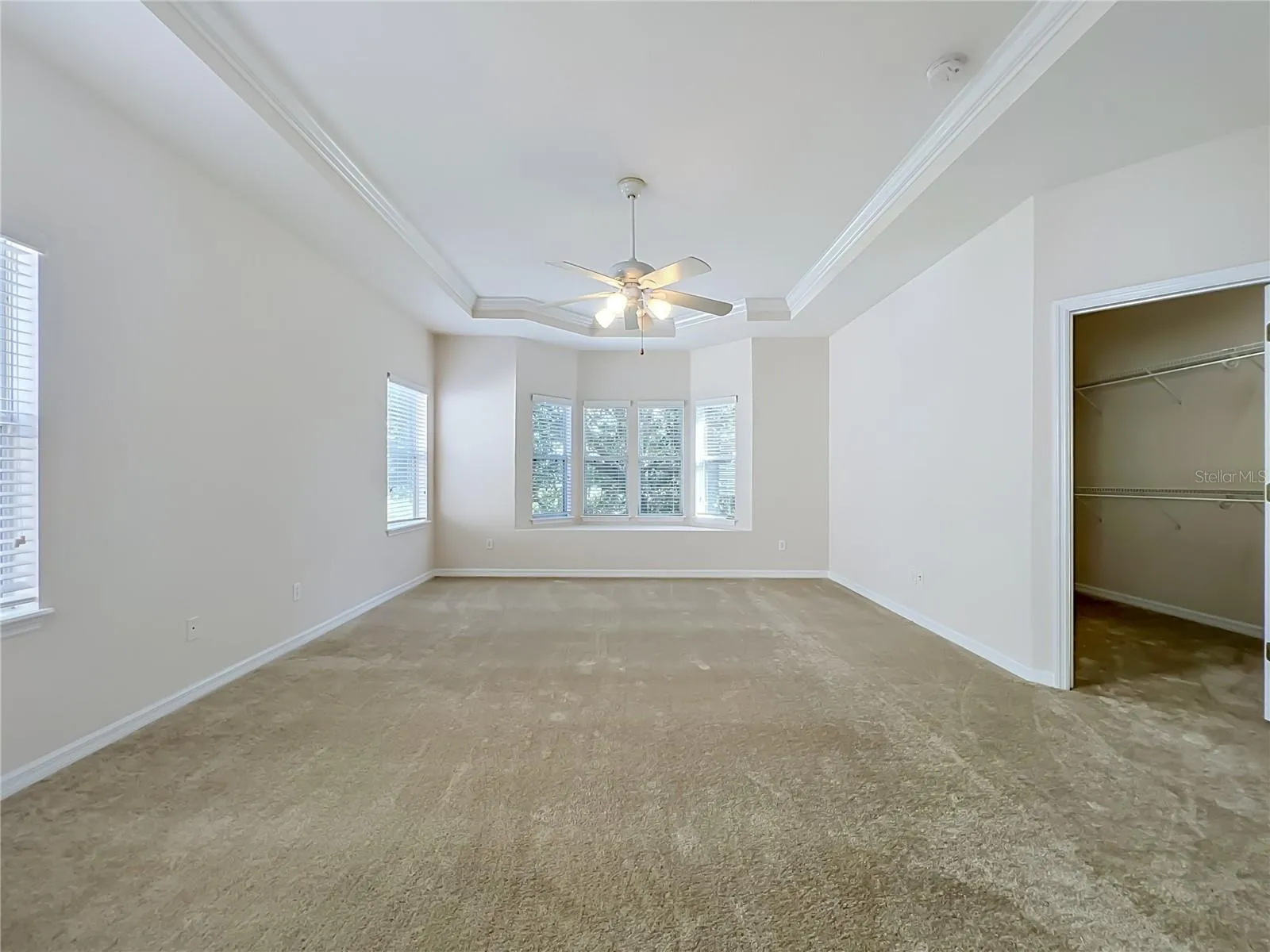 Primary bedroom features window seat, ceiling fan, tray ceiling, and large walk-in closet
