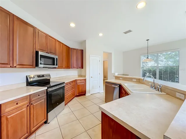 Wood cabinets, new appliances, closet pantry, a long breakfast bar, and ceramic tile floors