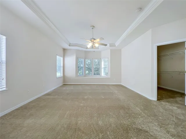 Primary bedroom features window seat, ceiling fan, tray ceiling, and large walk-in closet