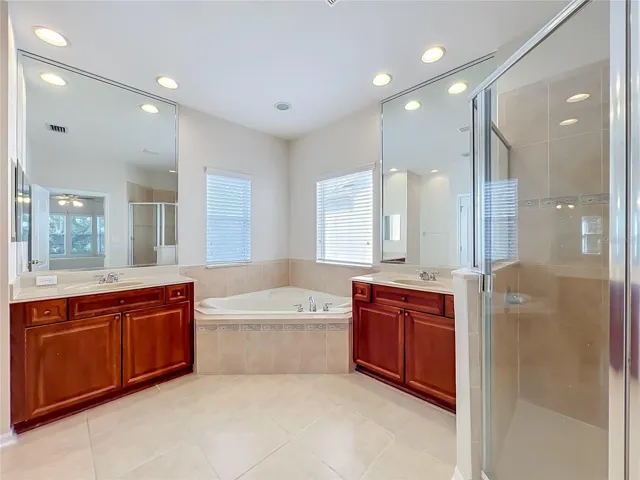 Primary bath features 18" ceramic tile floors, garden tub, dual vanities and sinks, separate walk-in shower