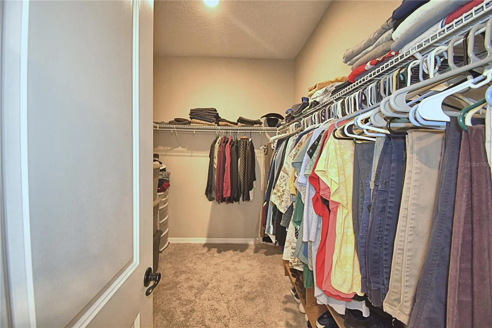 walk in closet behind door is more racks