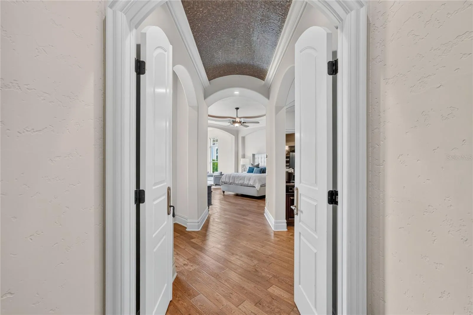 Formal double door entry to primary suite. Notice the intricate barrel mosaic tile ceiling. The left archway leads to the private access to pool terrace while the right archway to coffee bar/bath/closets.