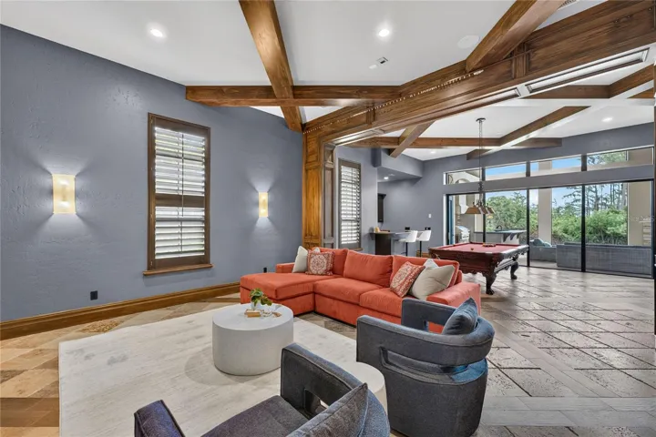 Game/Media room located off the family room. Beyond the pool table a wall of sliders pocket to open the screened lanai to this area for seamless outdoor/indoor entertaining and living.