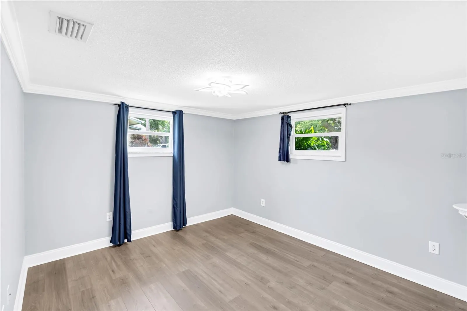 Two windows bring natural light into Bedroom 2, while updated flooring and generous proportions leave plenty of flexibility for furniture placement.