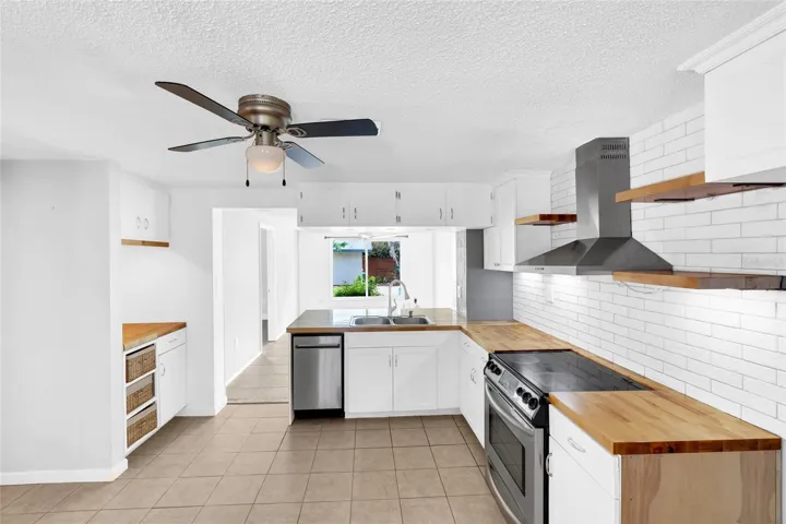 The updated kitchen features white cabinetry, butcher block countertops, stainless steel appliances and a clean subway tile backsplash.