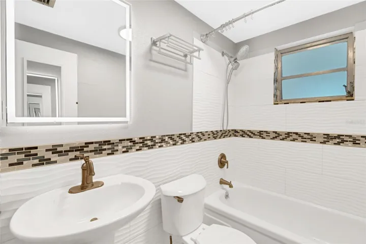 The guest bath includes a tub and shower combination, updated tile and a lighted mirror.