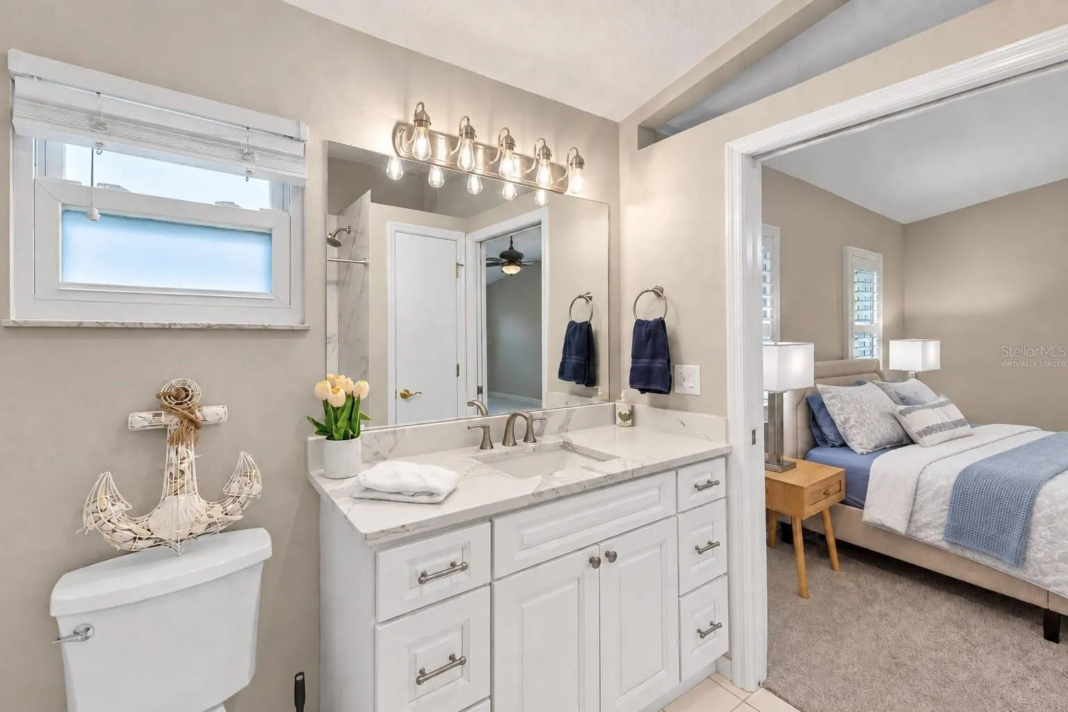 Bedroom 2 en suite bath with view to the bedroom. Virtually staged – bedding and decor digitally updated.