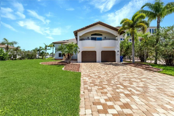 Front exterior with 2-car garage and brick-paver driveway.