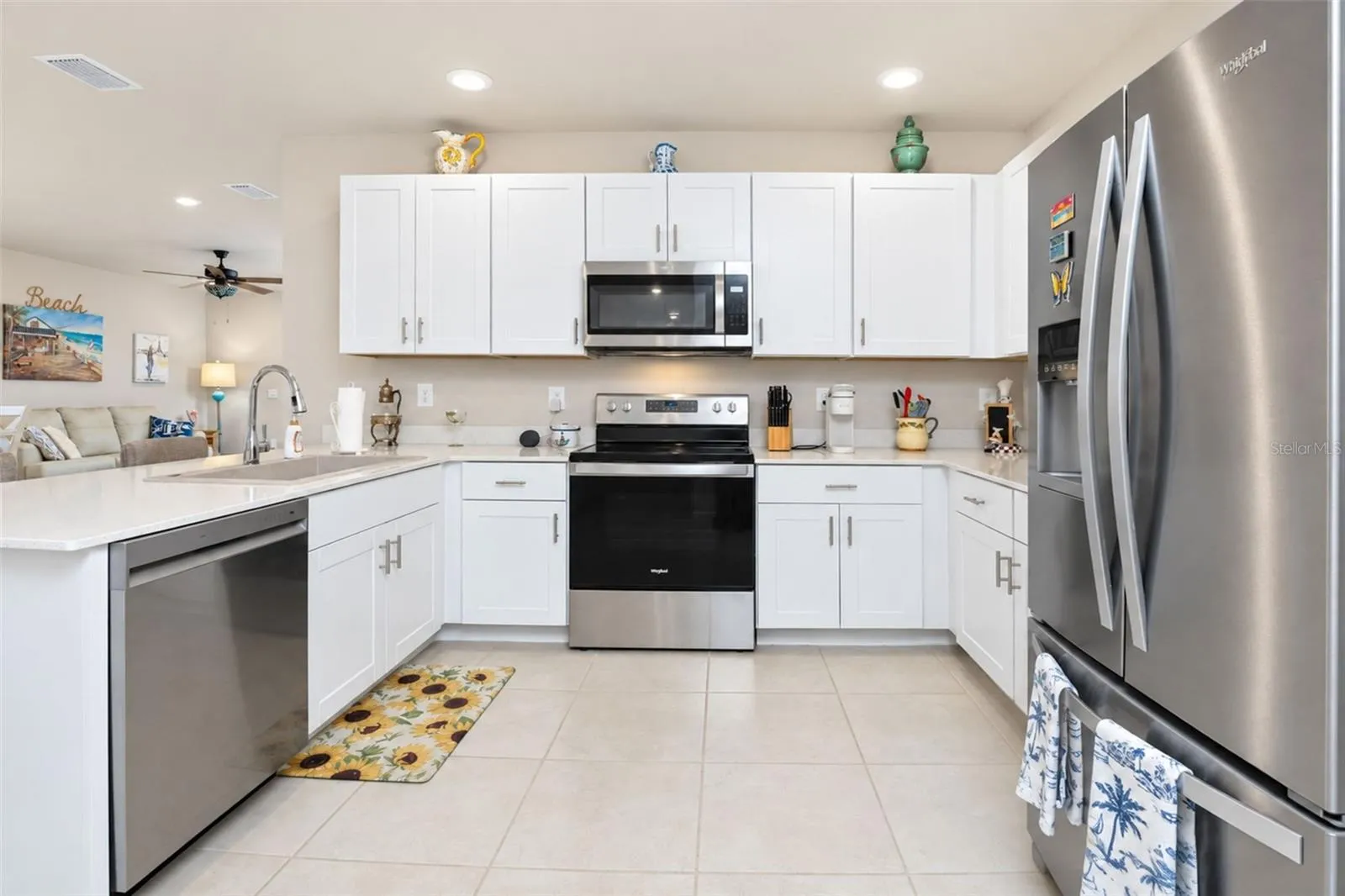 Open kitchen featuring ample cabinetry, pantry closet, breakfast bar, stainless steel appliances, and a new Ruvati resin sink with upgraded faucet.