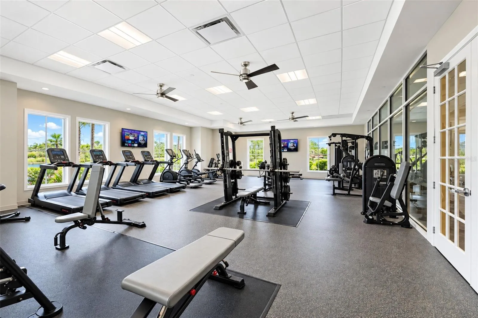 Bright and spacious fitness center featuring large windows with natural light, cardio and strength-training equipment, free weights, multiple workout stations and TVs for entertainment while you exercise.
