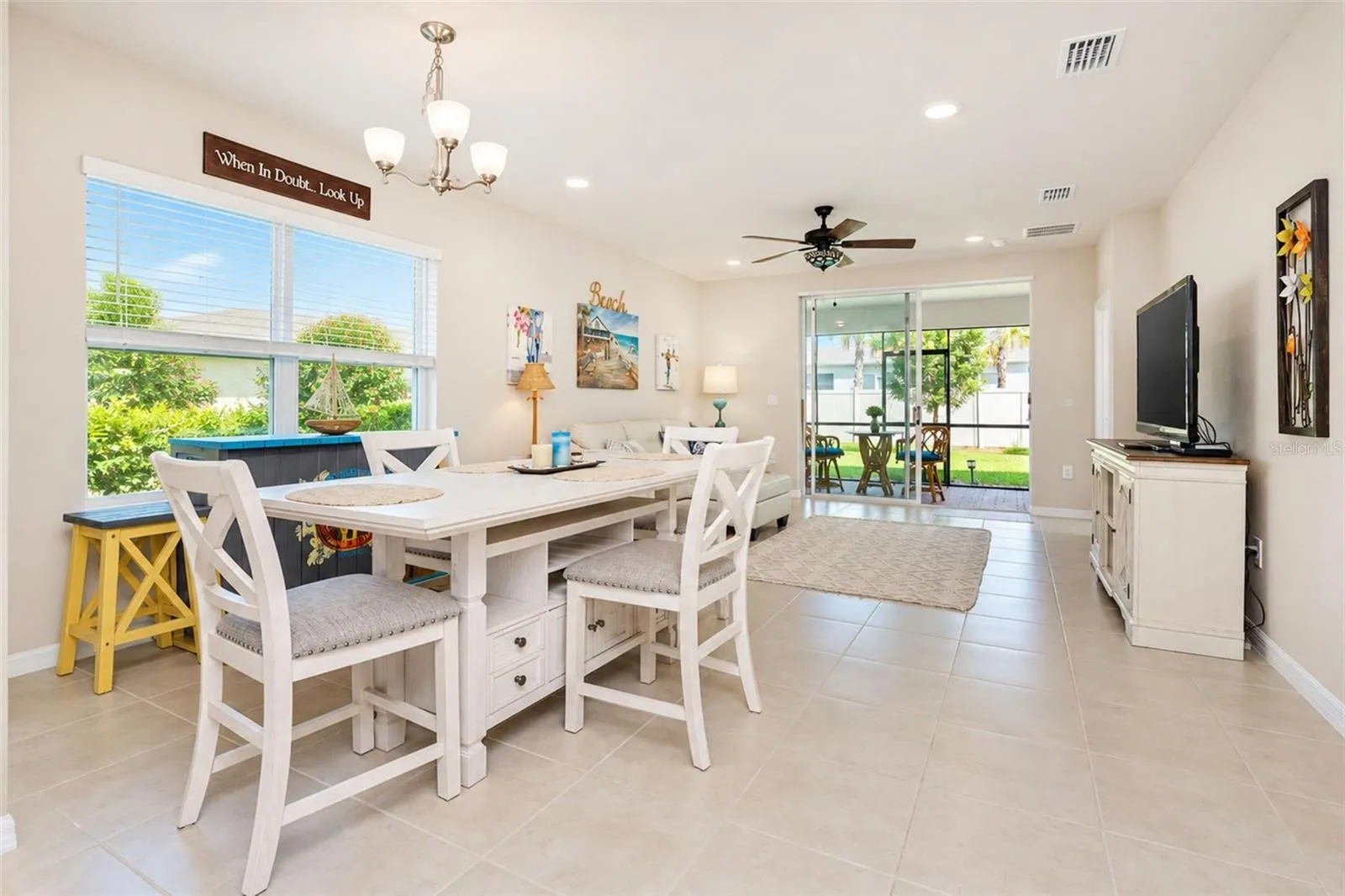 Bright, open-concept living and dining area with tile flooring, abundant natural light and an easy flow to the kitchen and screened lanai.