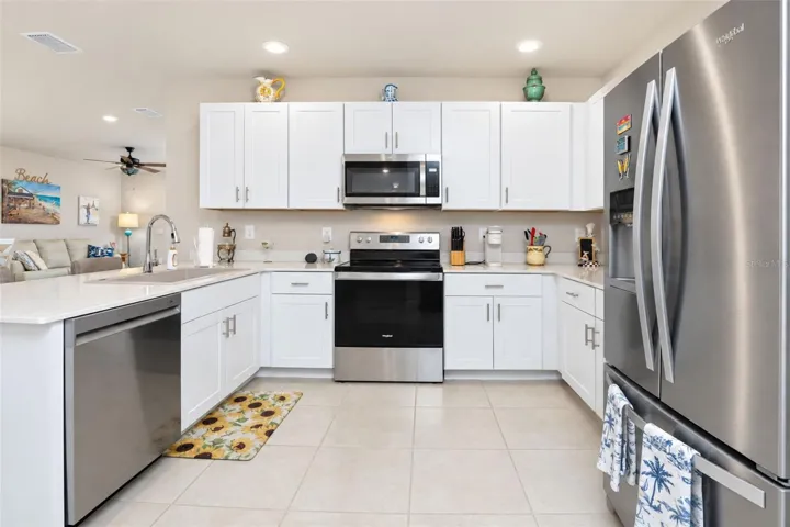 Open kitchen featuring ample cabinetry, pantry closet, breakfast bar, stainless steel appliances, and a new Ruvati resin sink with upgraded faucet.