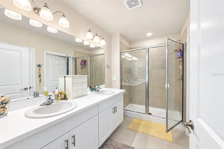 Private en-suite bath featuring dual sinks, generous vanity space, large tiled walk-in shower and conveniently located walk-in closet just steps from the shower.