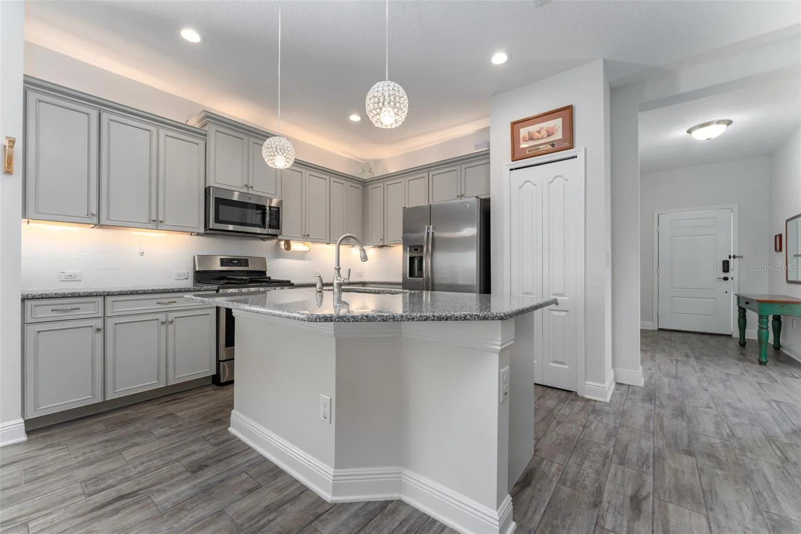 Kitchen with Center Island, Granite Tops, Neutral Cabinetry, Tile Backsplash & SS GE Appliances