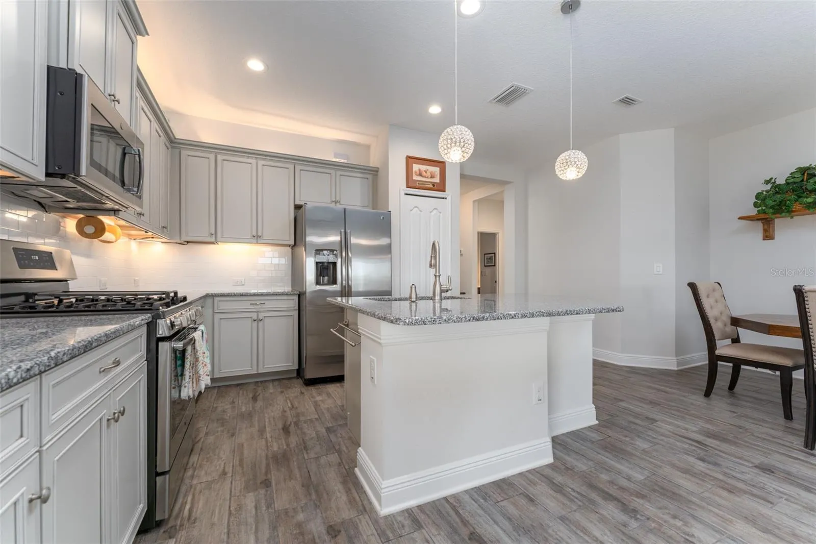 Kitchen with Center Island, Granite Tops, Neutral Cabinetry, Tile Backsplash & SS GE Appliances
