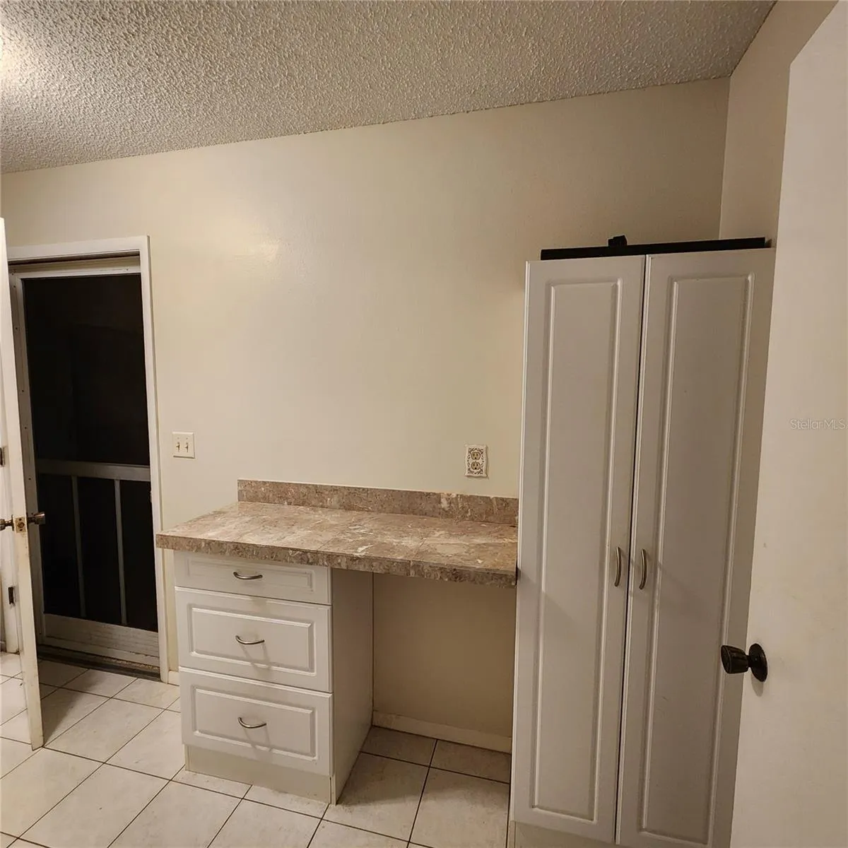 laundry room desk, storage cabinet, and door to garage