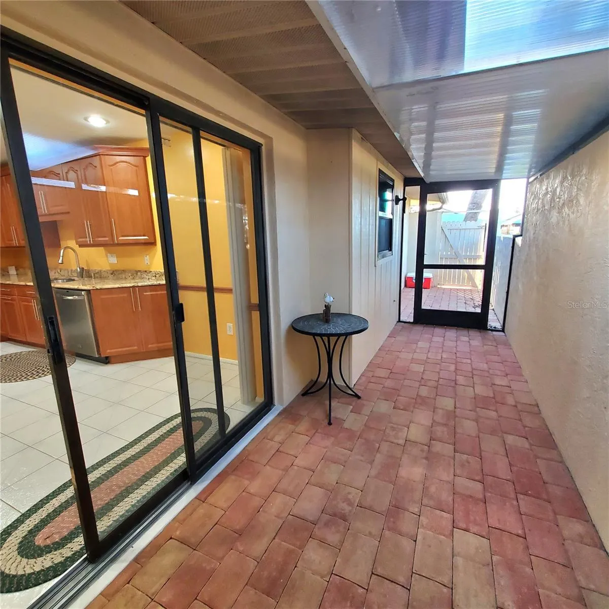 enclosed sitting area with pave stone and screen door to the back.