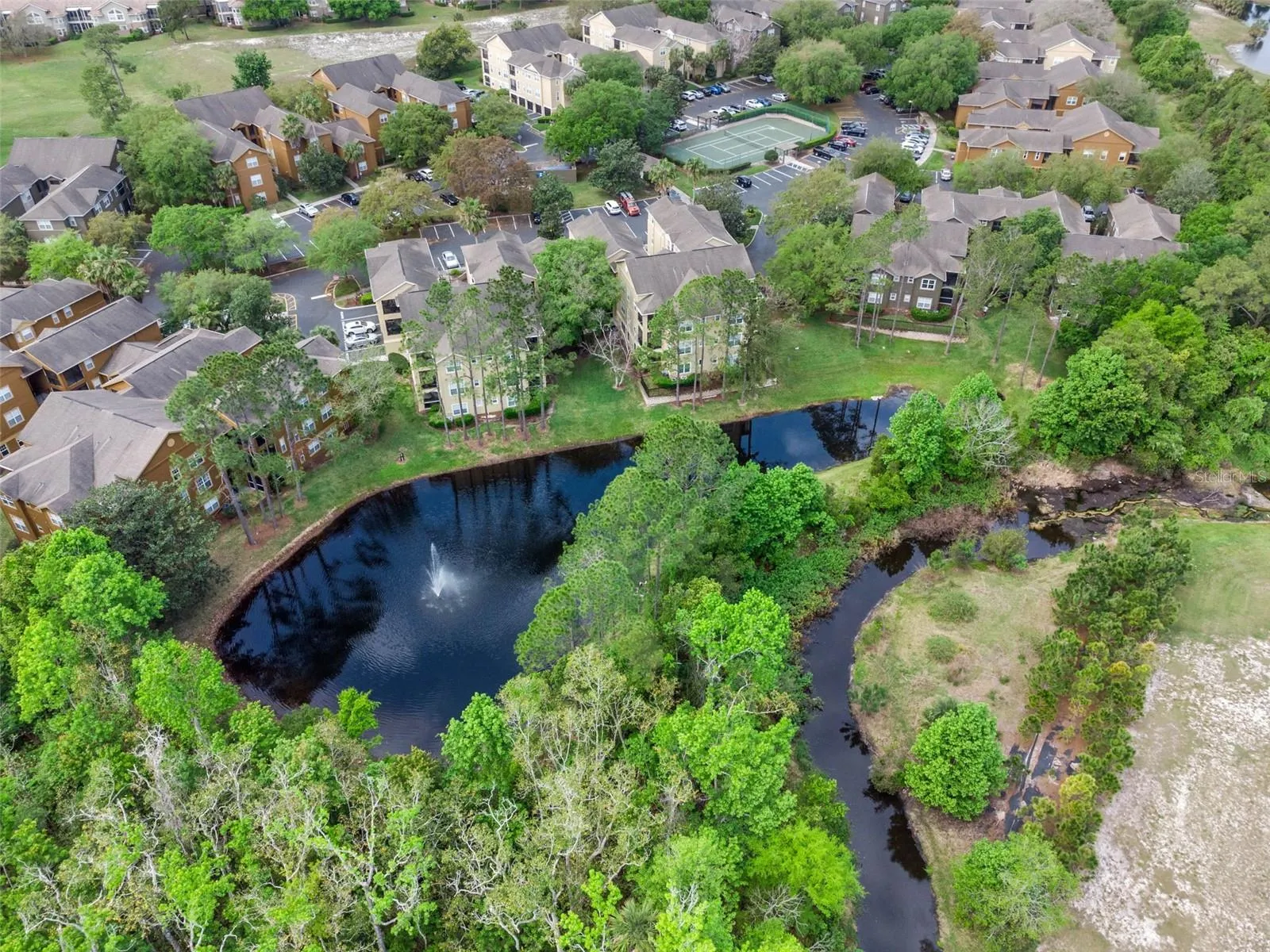 Aerial view of Sabal Point residential buildings, tree cover, and a pond with a fountain.