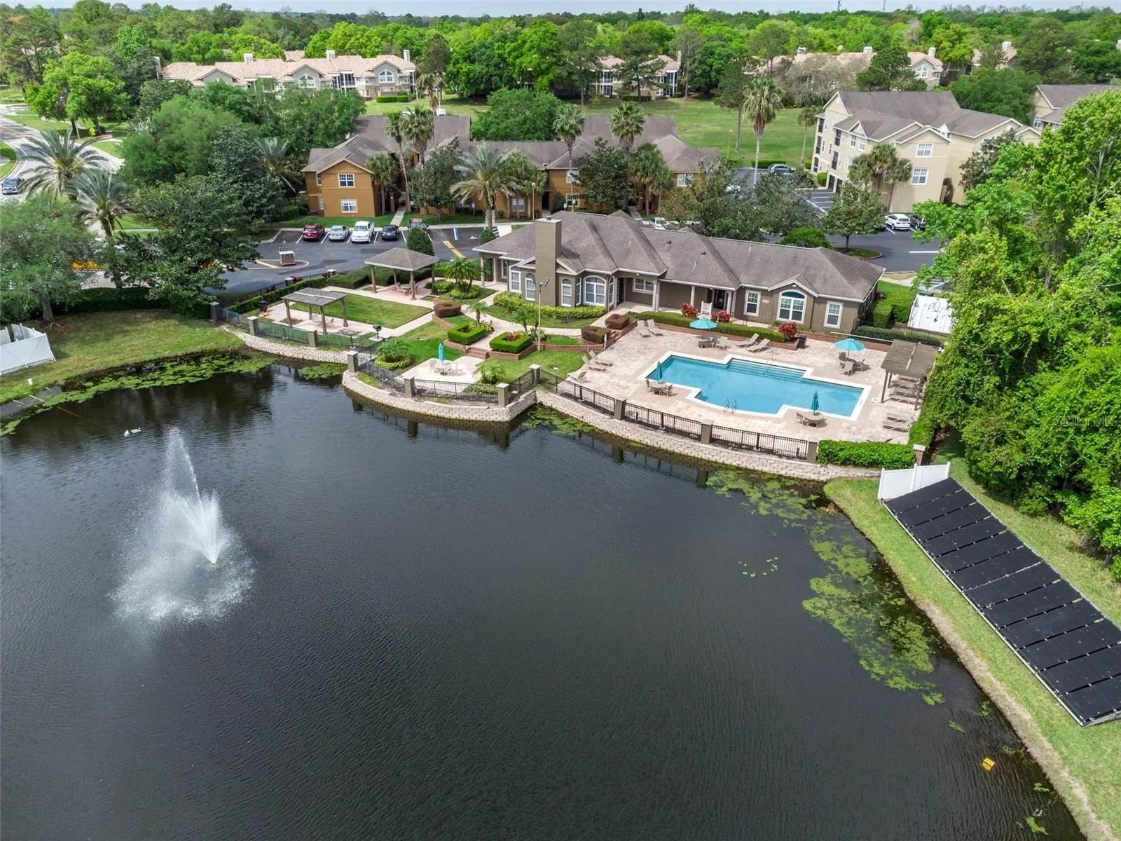 Aerial view of the Sabal Point clubhouse, pool, and residential buildings with the lake fountain in the foreground.