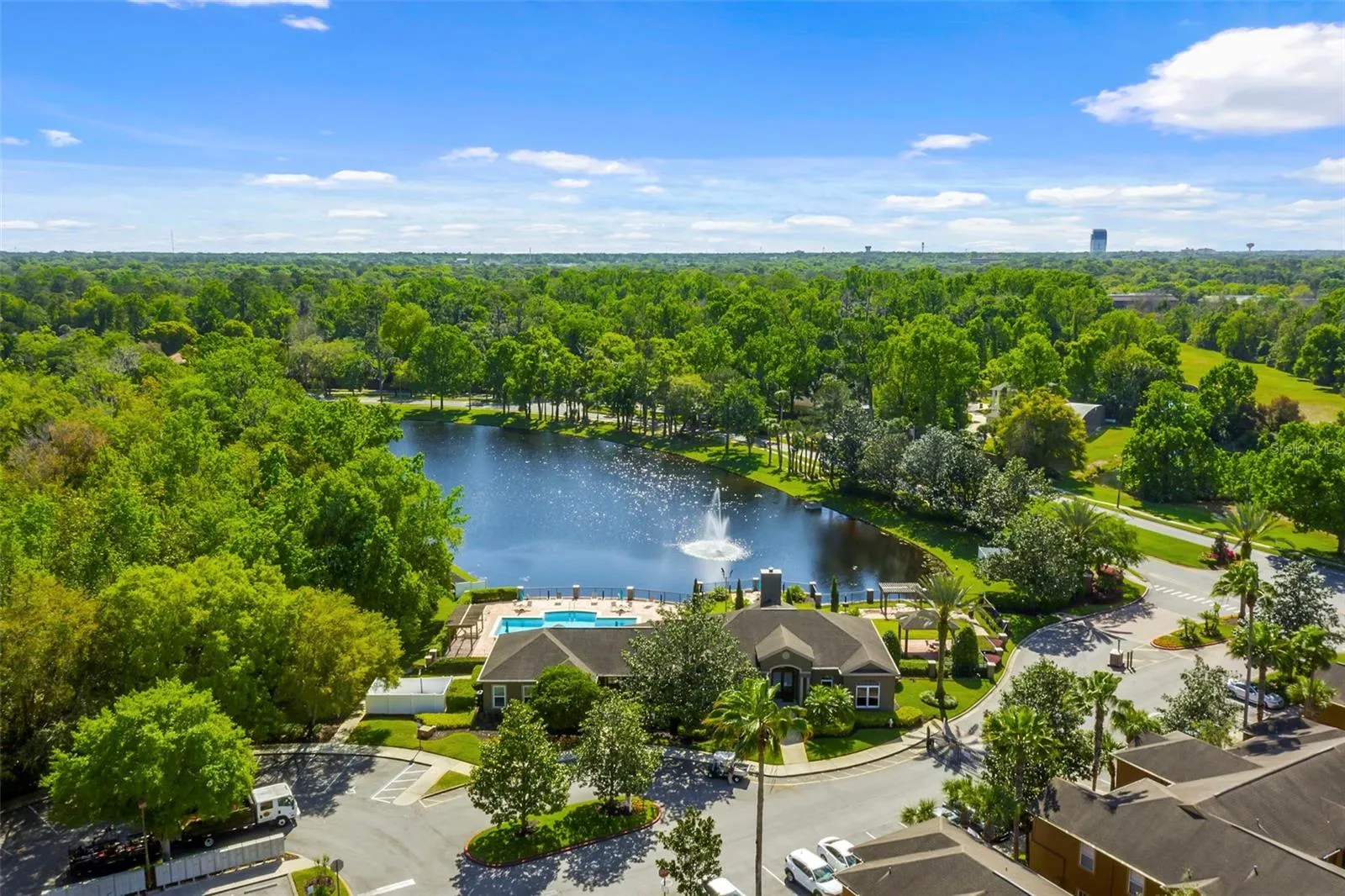 Distant aerial view of the Sabal Point lake and clubhouse surrounded by mature trees and neighborhood roads.