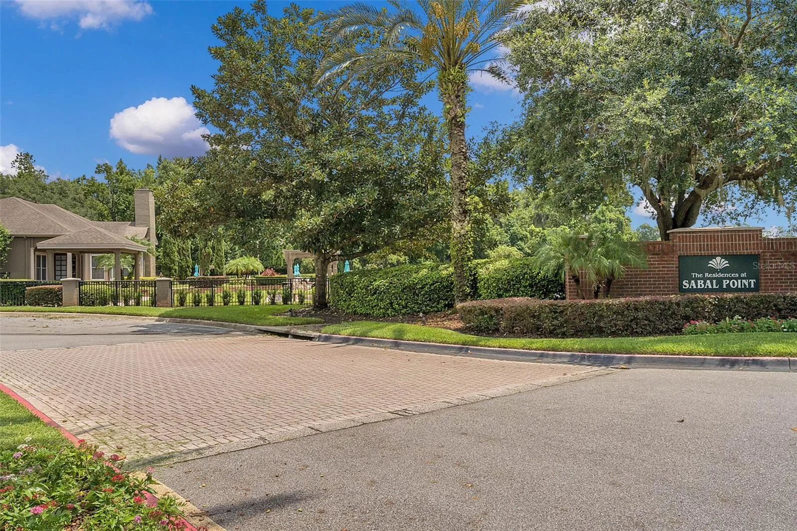 Brick entrance sign for The Residences at Sabal Point with a paver drive and the community clubhouse in the background.