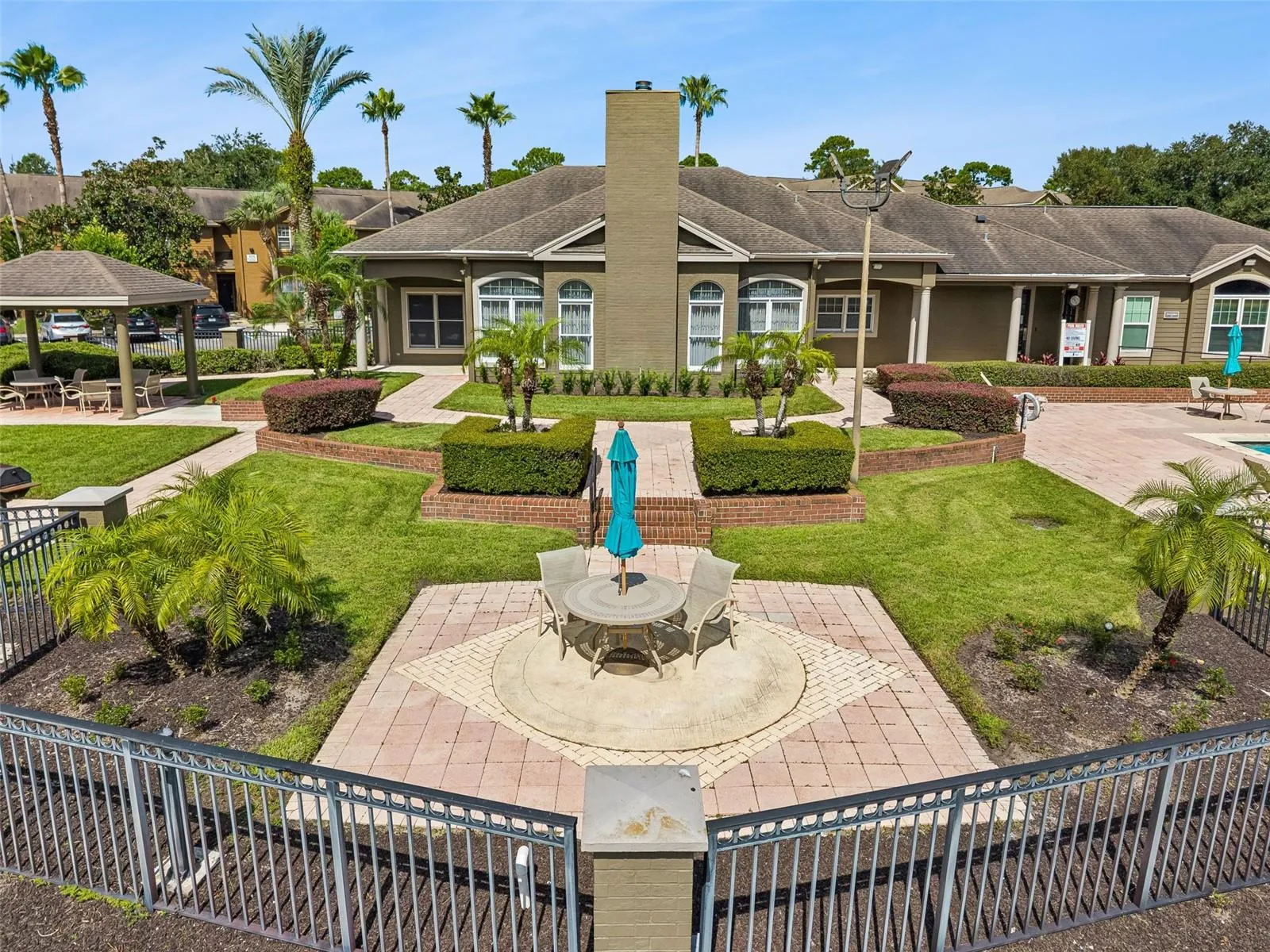 Sabal Point clubhouse and courtyard with a paver seating area, palm trees, and a gazebo.