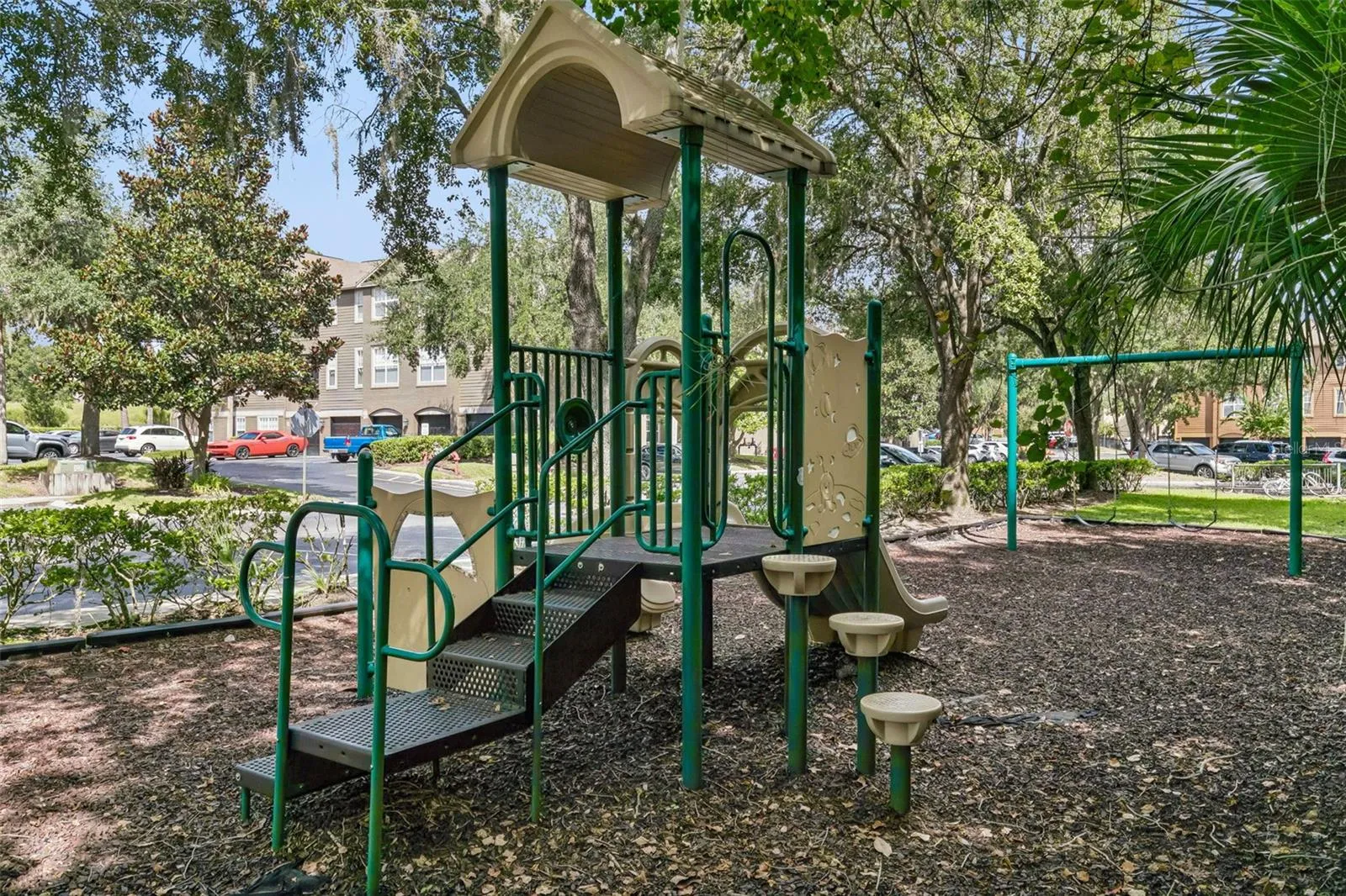 Sabal Point community playground with a slide, swing set, and wood-chip surfacing under shade trees.
