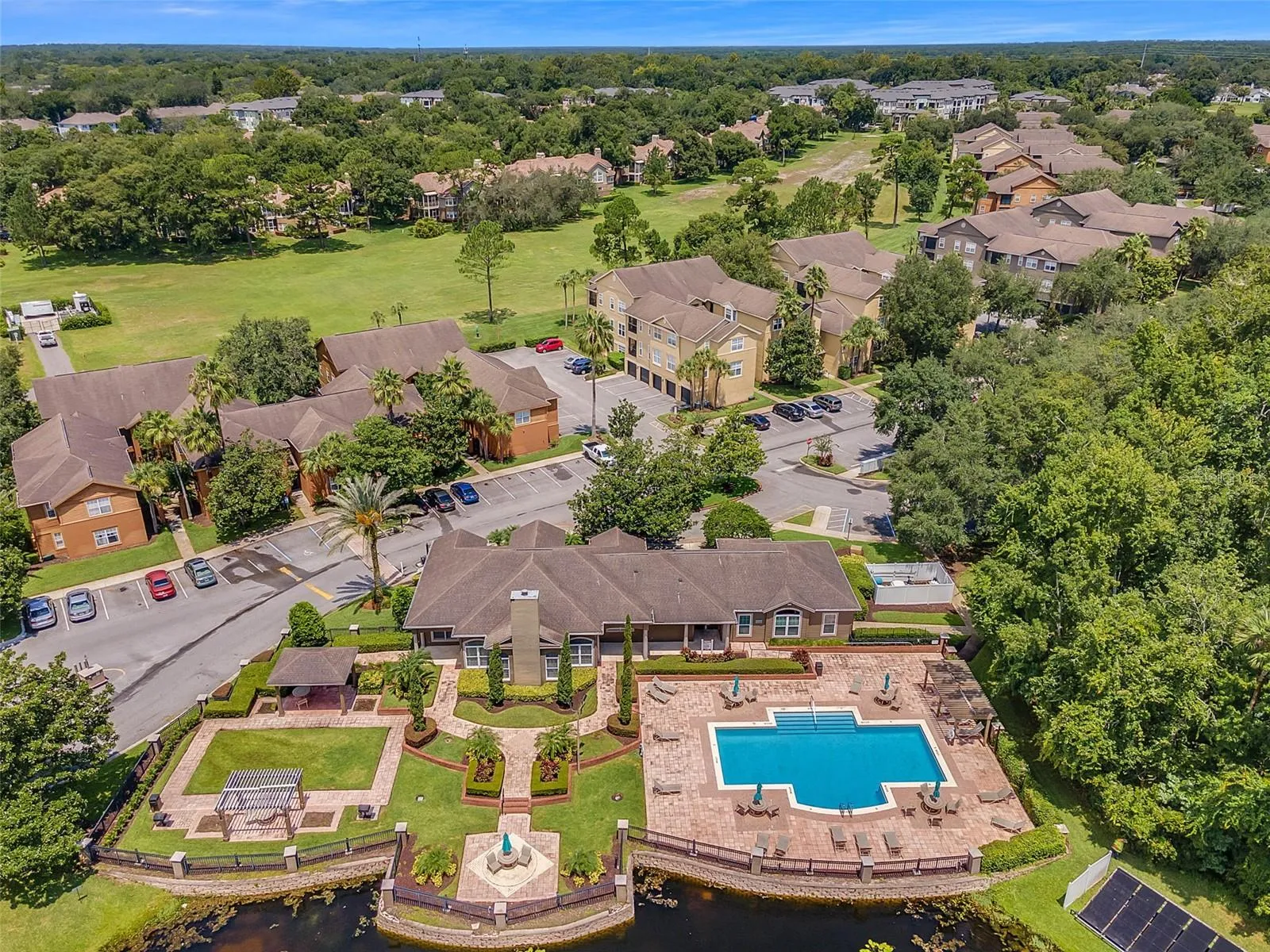 Aerial view of the Sabal Point community showing the clubhouse and pool in the foreground and a golf course and wooded area beyond.