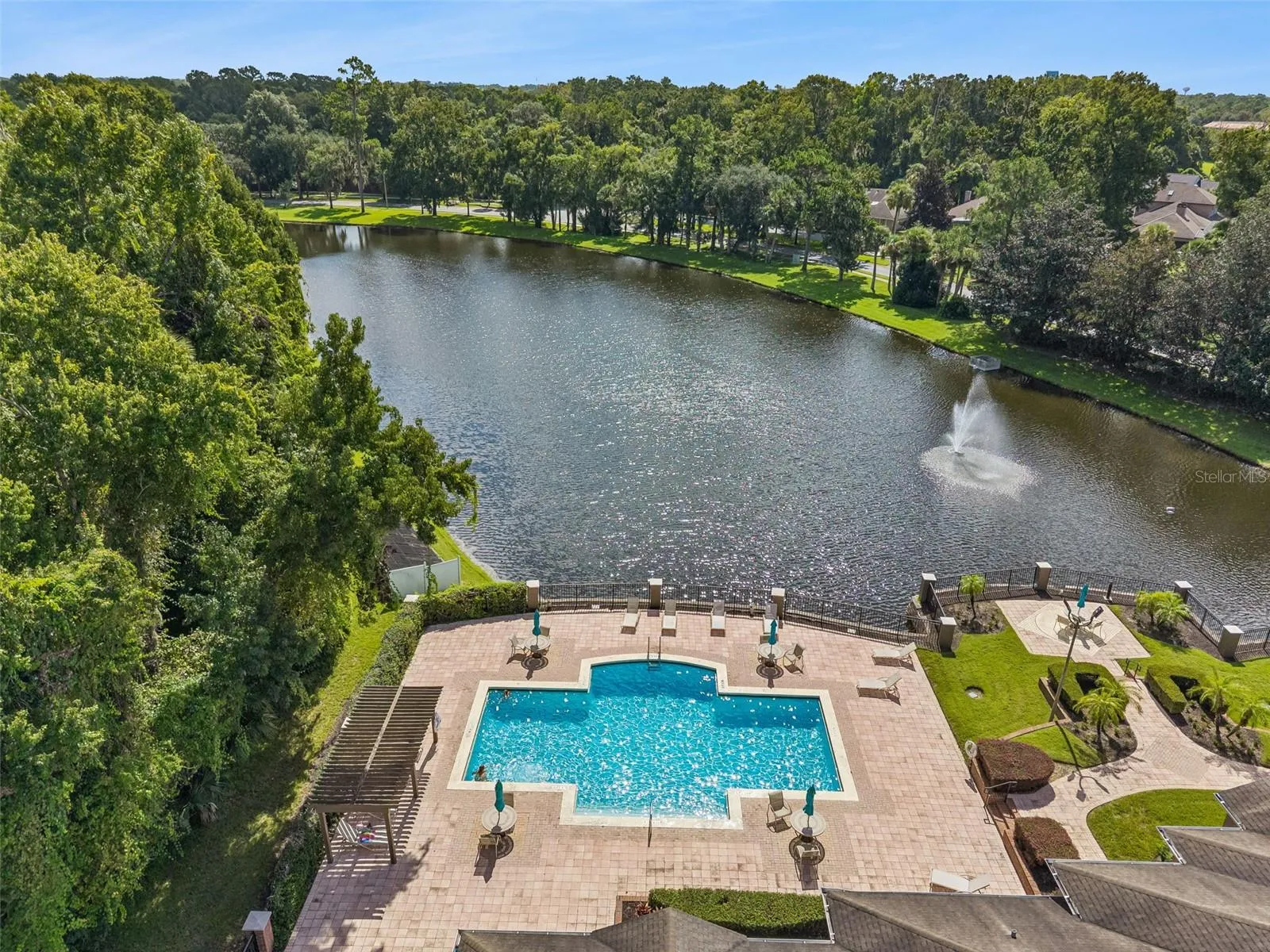 Aerial view of the Sabal Point pool deck along the lake shore, with the lake fountain and wooded surroundings.