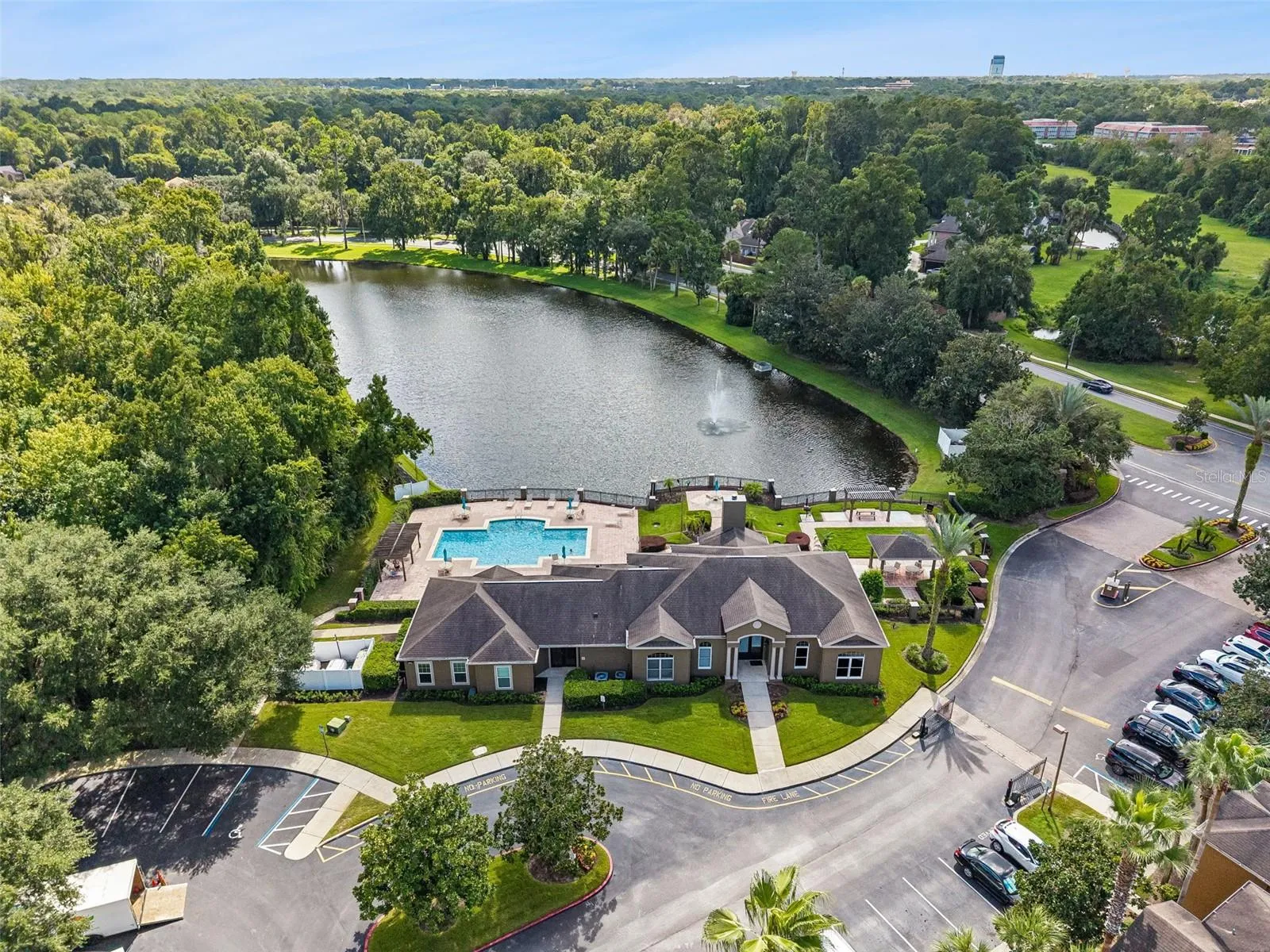 Aerial view of the Sabal Point clubhouse with its circular drive and parking, and the pool and lake beyond.