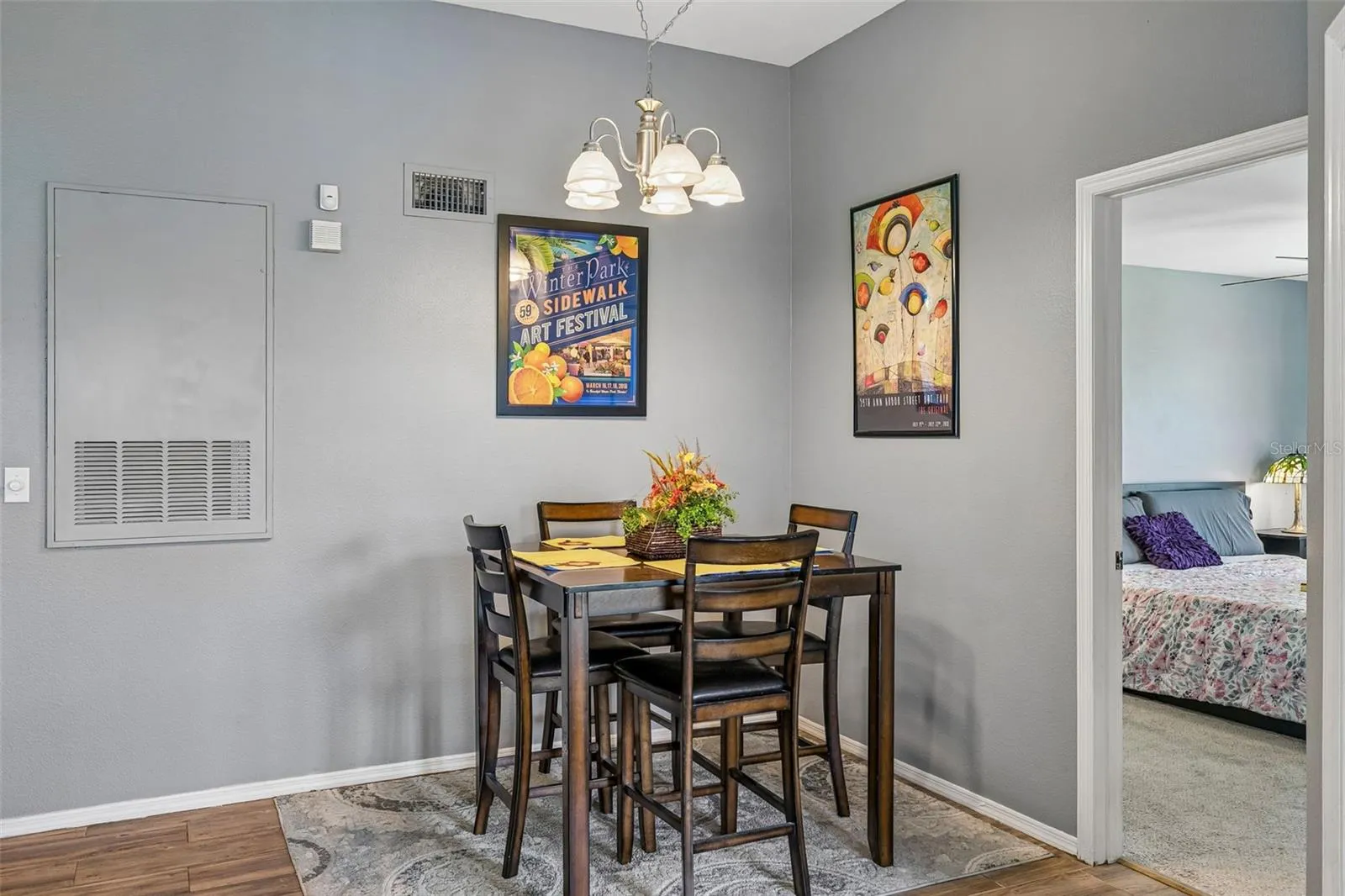 Dining area with a high-top table and chairs, a return-air vent, and an open doorway to a bedroom.