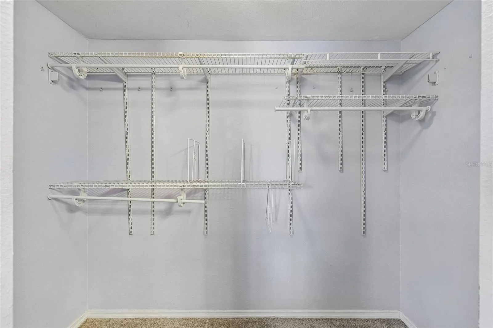 Primary walk-in closet with wire shelving and hanging rods on multiple levels.