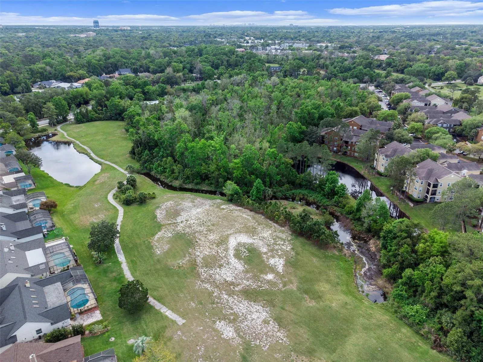 Aerial view of the Sabal Point community with a golf course, wooded area, and residential buildings and neighborhoods.