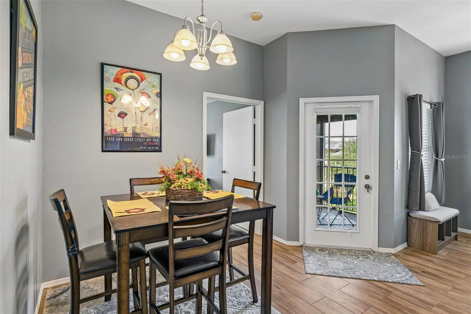 Dining room with a high-top table and four chairs, chandelier, and a glass-panel french door leading to the balcony.