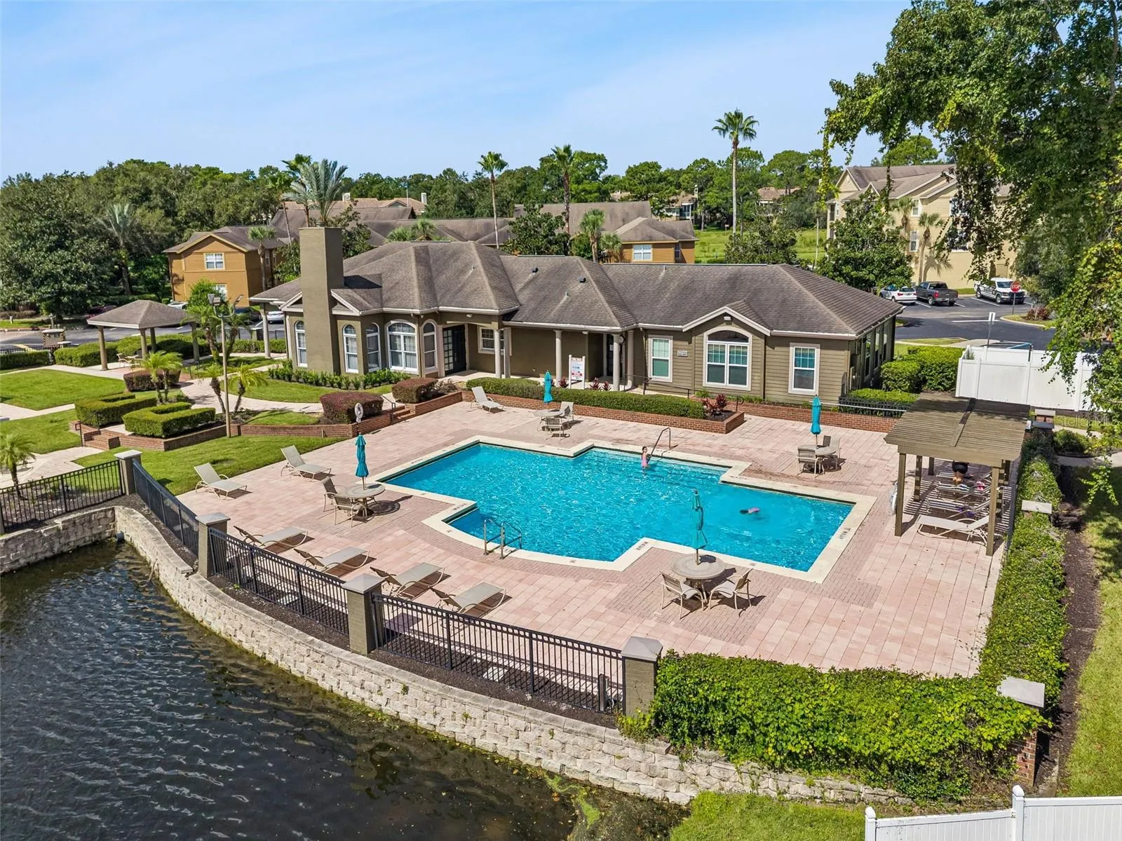 Aerial view of the Sabal Point community pool, paver pool deck with loungers, pergola, and clubhouse.