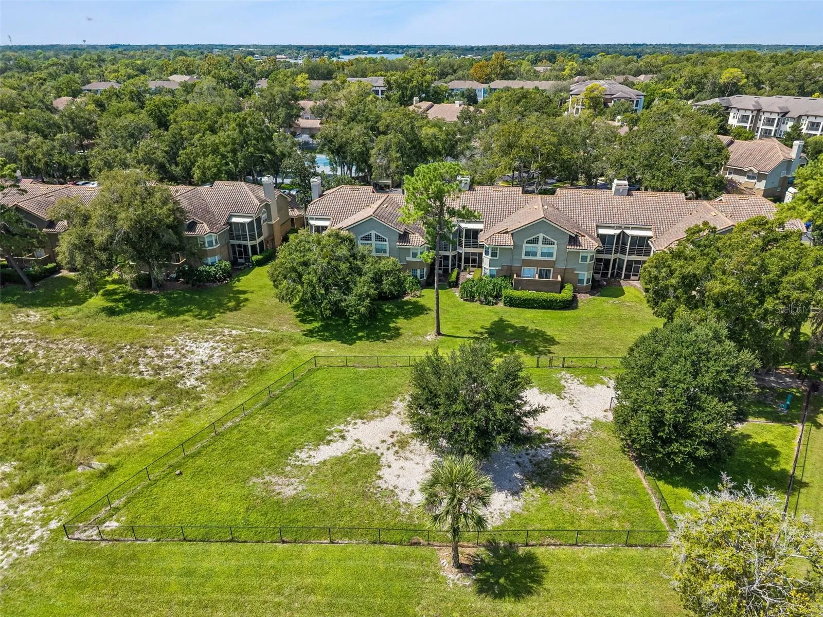 Aerial view of the rear of the building at Summit Ridge in Longwood, FL, with a fenced green space and surrounding trees.