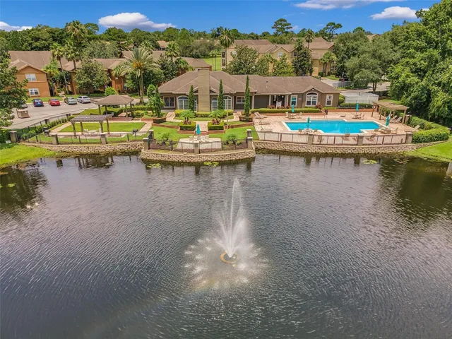 View across the lake and fountain to the Sabal Point clubhouse, pool, gazebos, and landscaped lakefront.