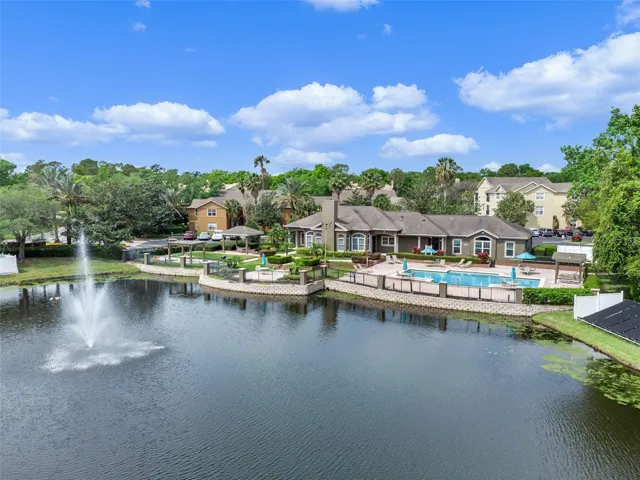 Lake with a fountain in the foreground and the Sabal Point clubhouse, pool, and residential buildings on the far shore.