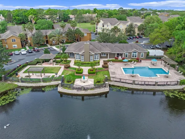 Aerial view across the lake toward the Sabal Point clubhouse, pool, and surrounding residential buildings.