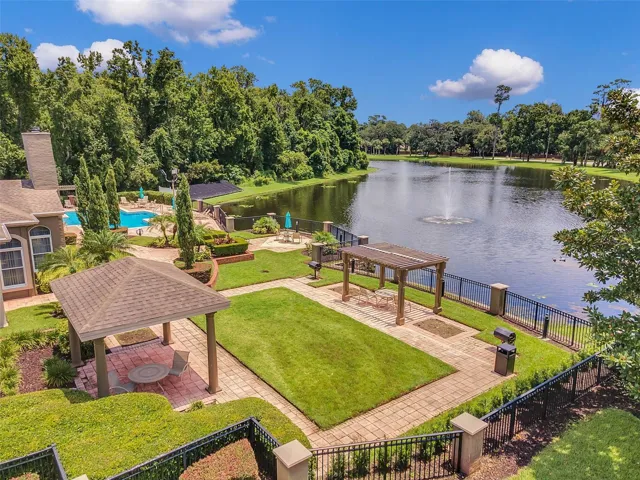 Elevated view of the Sabal Point lakeside gazebo, pergola, lawn, and grill area beside the lake, with the pool at left.