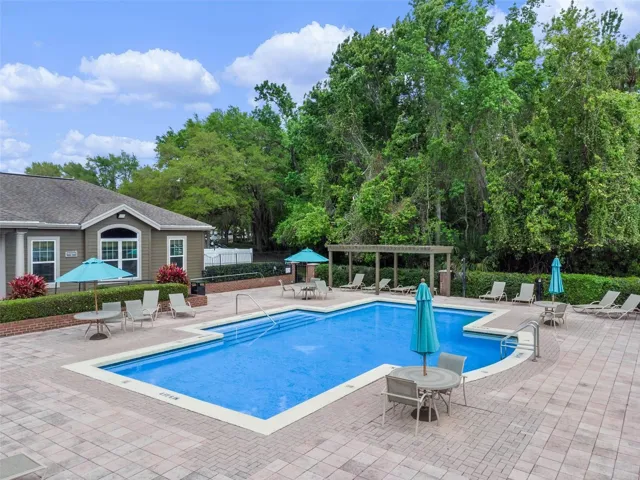 Sabal Point community swimming pool with teal umbrellas, lounge chairs, and a paver deck next to the clubhouse.