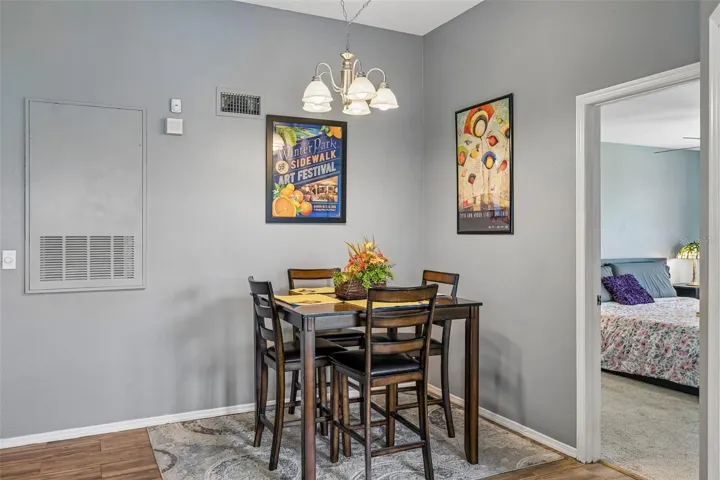 Dining area with a high-top table and chairs, a return-air vent, and an open doorway to a bedroom.