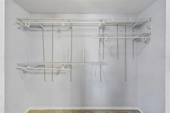 Primary walk-in closet with wire shelving and hanging rods on multiple levels.