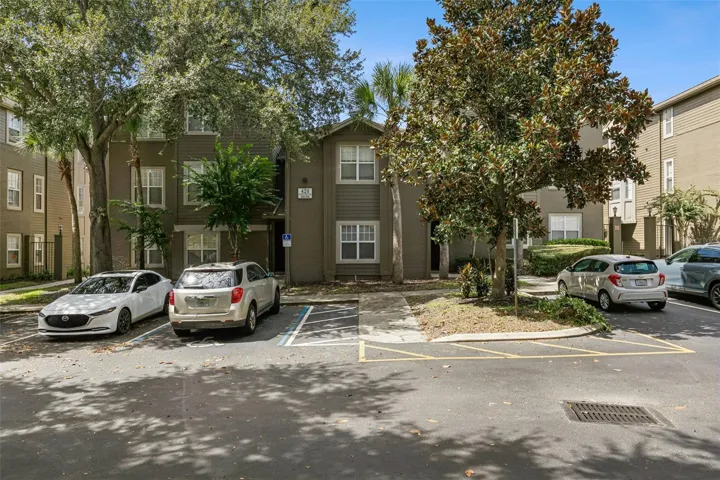 Front exterior of the three-story condominium building at 420 Summit Ridge Place in Longwood, FL, with mature trees and open parking in front.