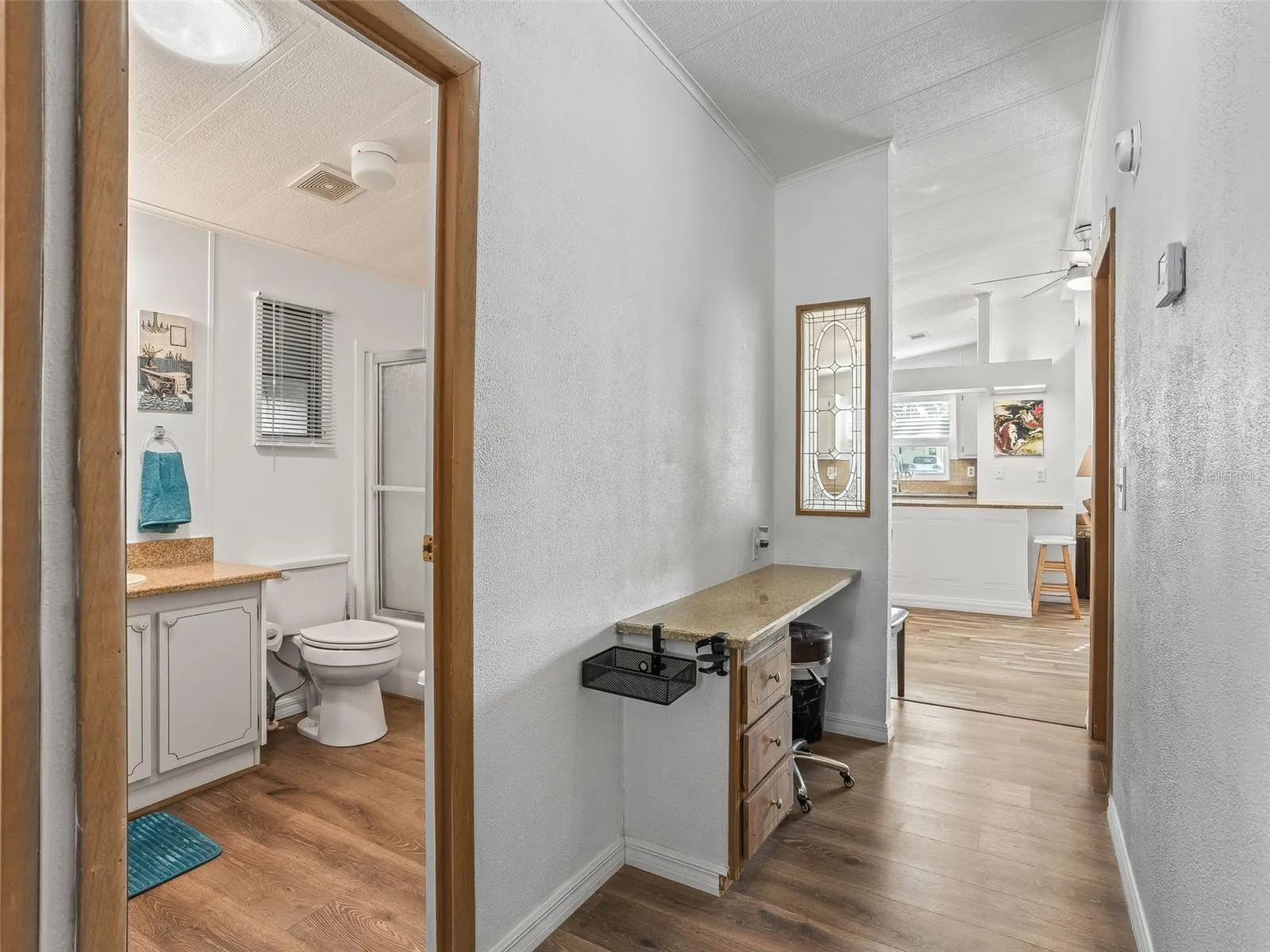 View of HALLWAY - Shows BATHROOM #2 (L) and DESK (L Center) and opening to MAIN LIVING AREA at end of hallway.