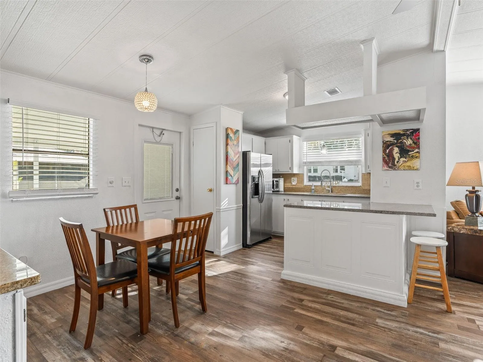 View of DINING ROOM (front L), FRONT DOOR ENTRANCE (middle L), &amp; KITCHEN (back R). Note attractive WOOD LAMINATE FLOORS which flow throughout the home.